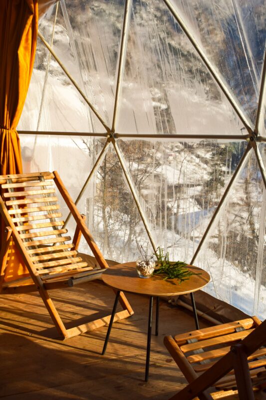 chaise et table basse en bois à l'intérieur d'un dôme géodésique en hiver